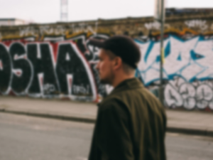 Man in baseball cap walking passed a graffit covered wall