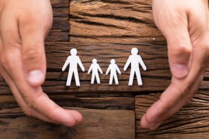 Hands protecting figures representing a family