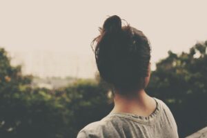 Woman with her back towards the viewer looking out over an outdoor landscape